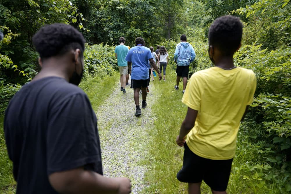 Students Giovanni Pierre, foreground left, and Aaron Overton, foreground right, walk behind camp educator Jamil Boykin, center, during a hike at Mass Audubon's Boston Nature Center and Wildlife Sanctuary, in Mattapan. (Steve Senne/AP)