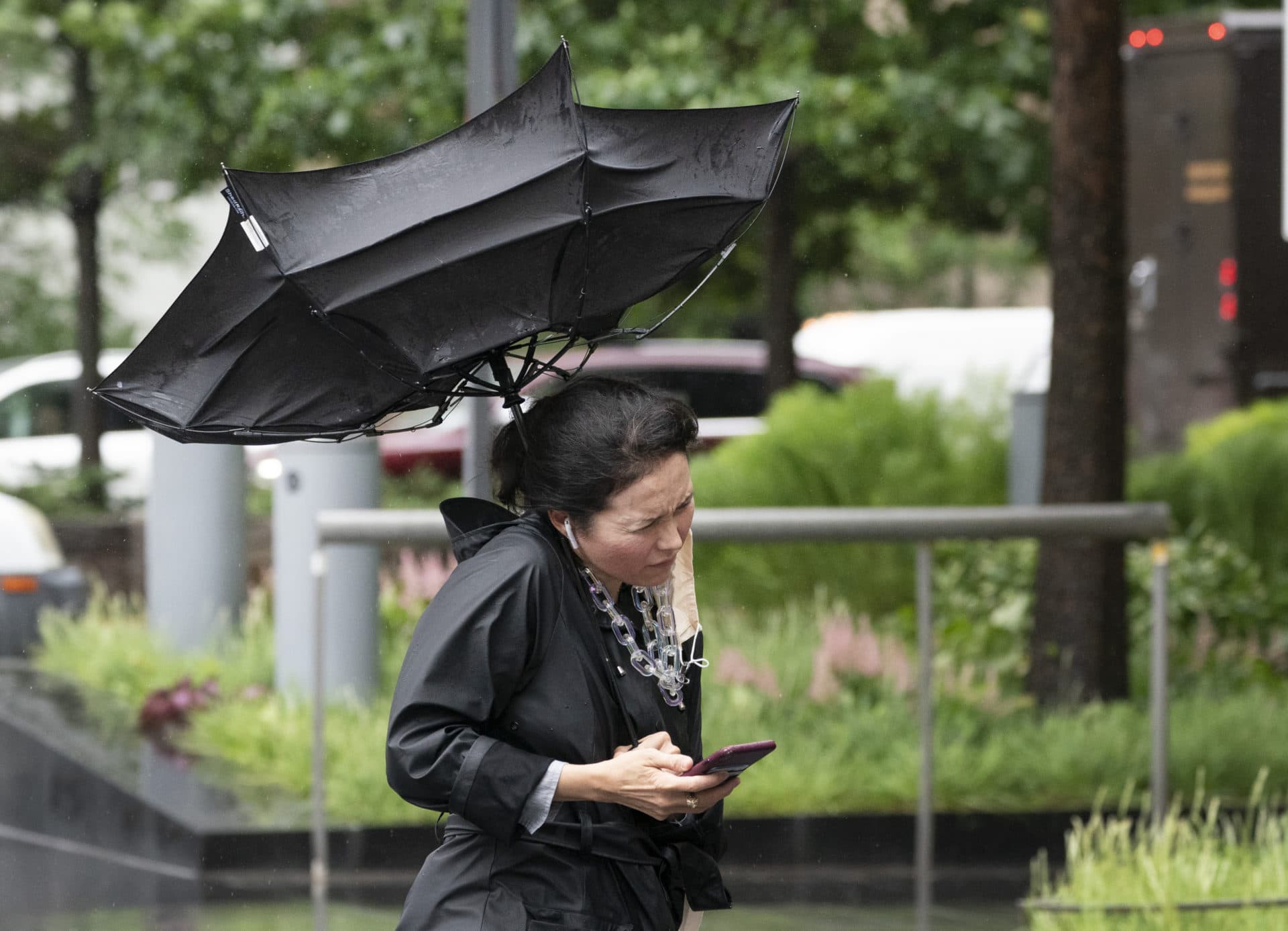 A woman's umbrella is flipped inside out as she walks on a rainy and windy New York street as Elsa bears down on the city. (Mark Lennihan/AP)
