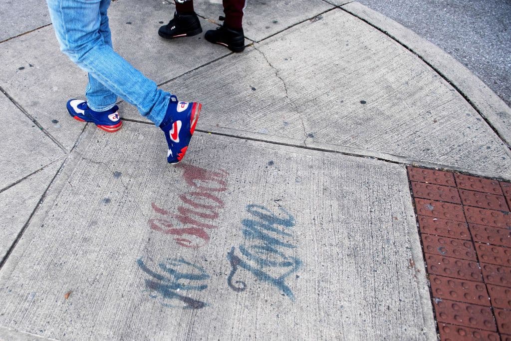 Two men walk past a sign spray painted on the sidewalk stating "No Shoot Zone" in Baltimore, Maryland, on Dec. 17, 2018. (Jim Watson/AFP/Getty Images)