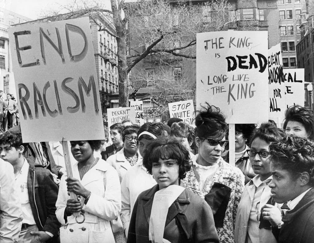 Demonstrators holding signs reading "end racism" and "The King is Dead, Long Live The King" gather on the Boston Common opposite the Massachusetts State House on April 5, 1968, the day after Martin Luther King Jr. was assassinated. (William Ryerson/The Boston Globe via Getty Images)