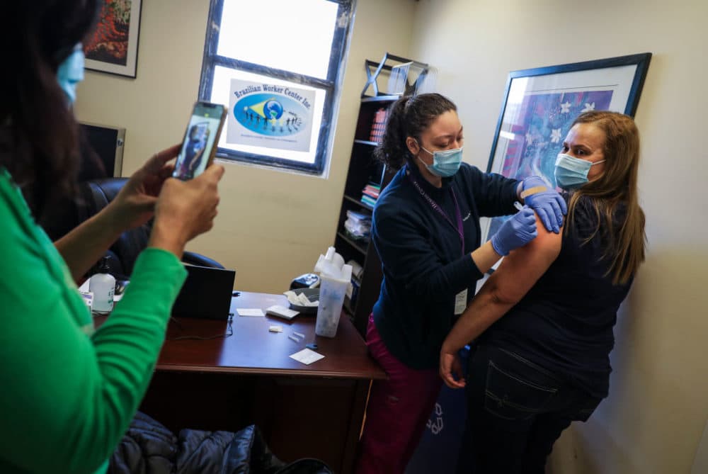 A person takes a photo of someone receiving a vaccine at a clinic hosted by the Brazilian Workers Center in Boston's Allston on March 19, 2021. Whittier Street Health Center administered 200 vaccines to the community. (Erin Clark/The Boston Globe via Getty Images)