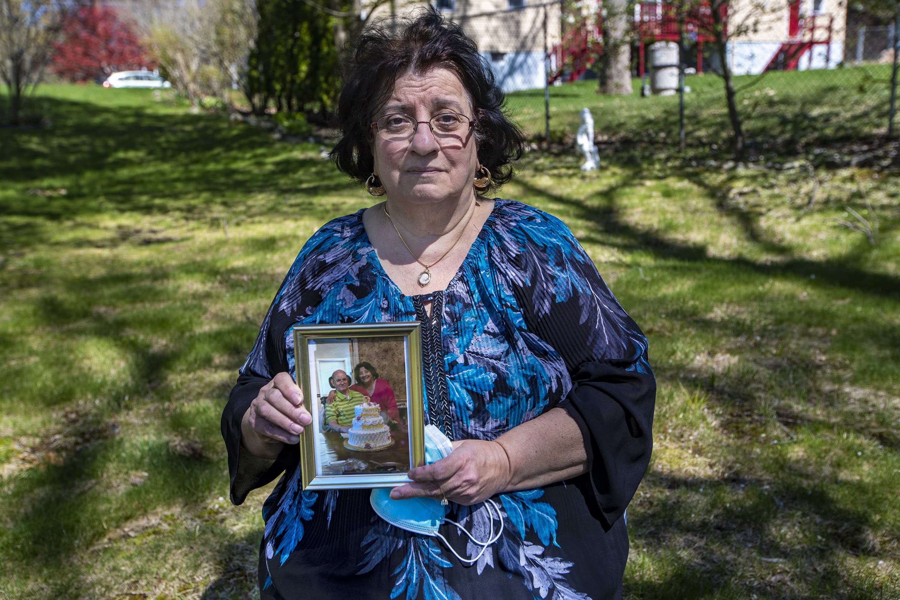 Stella Kazantzas holding a photograph of herself and her husband Nick in 2019, celebrating their 50th anniversary. (Jesse Costa/WBUR)