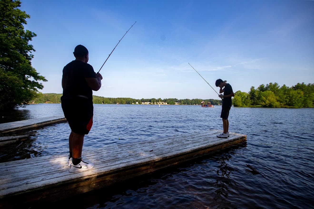 Chaun’cee Smith and Josiah Lopez fish off a dock in Lake Lashaway at Camp Atwater in North Brookfield. (Jesse Costa/WBUR)