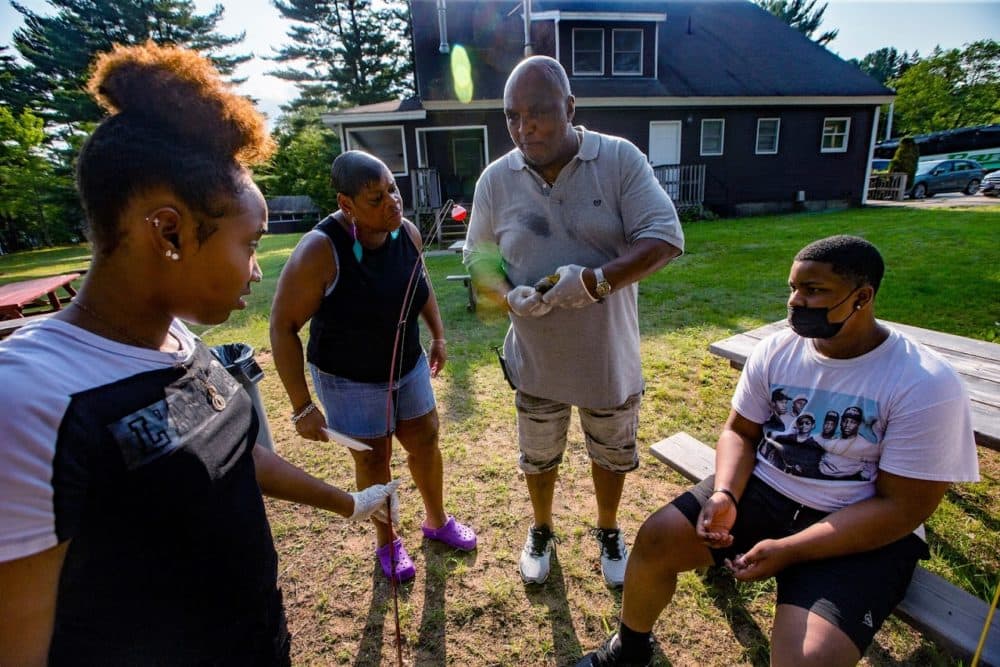 Director of Maintenance for Camp Atwater Buck Gee demonstrates to campers how to remove a hook from a sun fish. Gee attended the camp as a child and has been working here for 40 years. (Jesse Costa/WBUR)