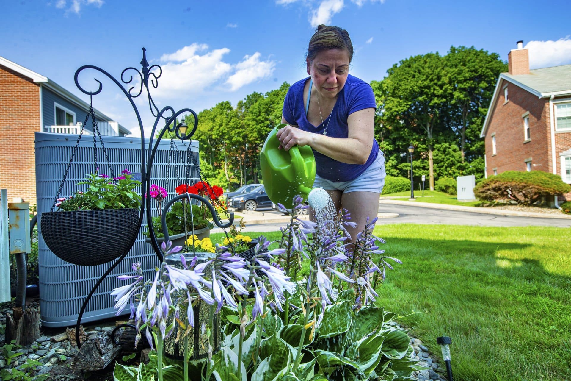 Susana Carella waters the small garden she manages at her Chelsea townhouse. (Jesse Costa/WBUR)