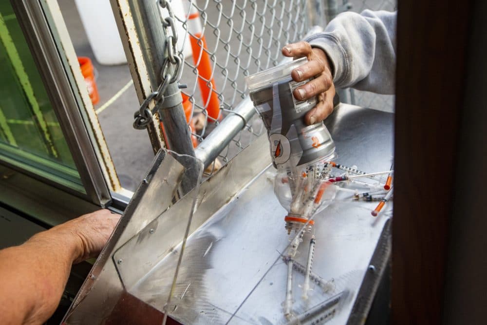A man dumps out a plastic drink bottle full of syringes onto the counter at the Southampton Street Shelter in Boston as part of a syringe buy back project run by the Community Syringe Redemption Program. (Jesse Costa/WBUR)