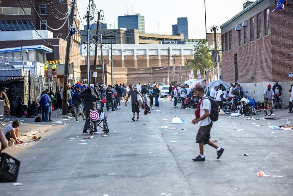 The scene on Atkinson Street of people experiencing homelessness and substance use disorders waiting outside of the entrance of the Southampton Street Shelter early on a Monday morning. (Jesse Costa/WBUR)