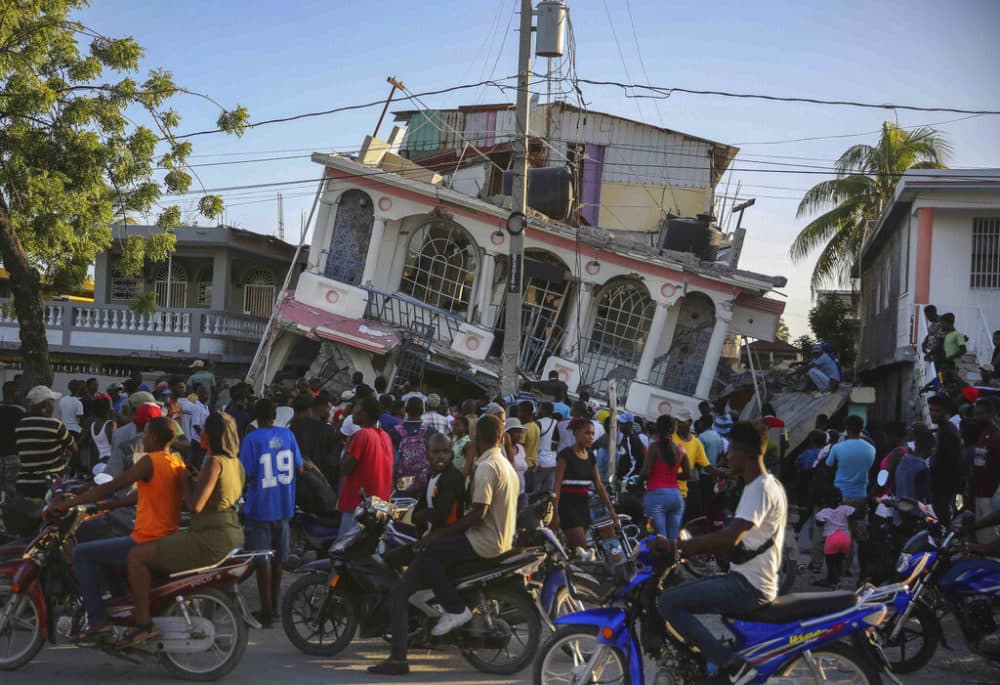 People gather outside the Petit Pas Hotel, destroyed by the earthquake in Les Cayes, Haiti, Saturday. (Joseph Odelyn/AP)