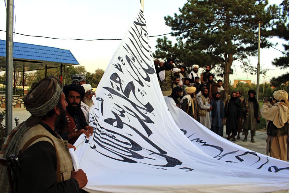 Taliban fighters raise their flag at the Ghazni provincial governor's house, in Ghazni, southeastern, Afghanistan, Sunday, Aug. 15, 2021. (Gulabuddin Amiri/AP)