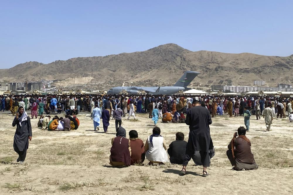 Hundreds of people gather near a U.S. Air Force C-17 transport plane at the perimeter of the international airport in Kabul, Afghanistan, Monday, Aug. 16, 2021. On Monday, the U.S. military and officials focus was on Kabul's airport, where thousands of Afghans trapped by the sudden Taliban takeover rushed the tarmac and clung to U.S. military planes deployed to fly out staffers of the U.S. Embassy, which shut down Sunday, and others. (Shekib Rahmani/AP)