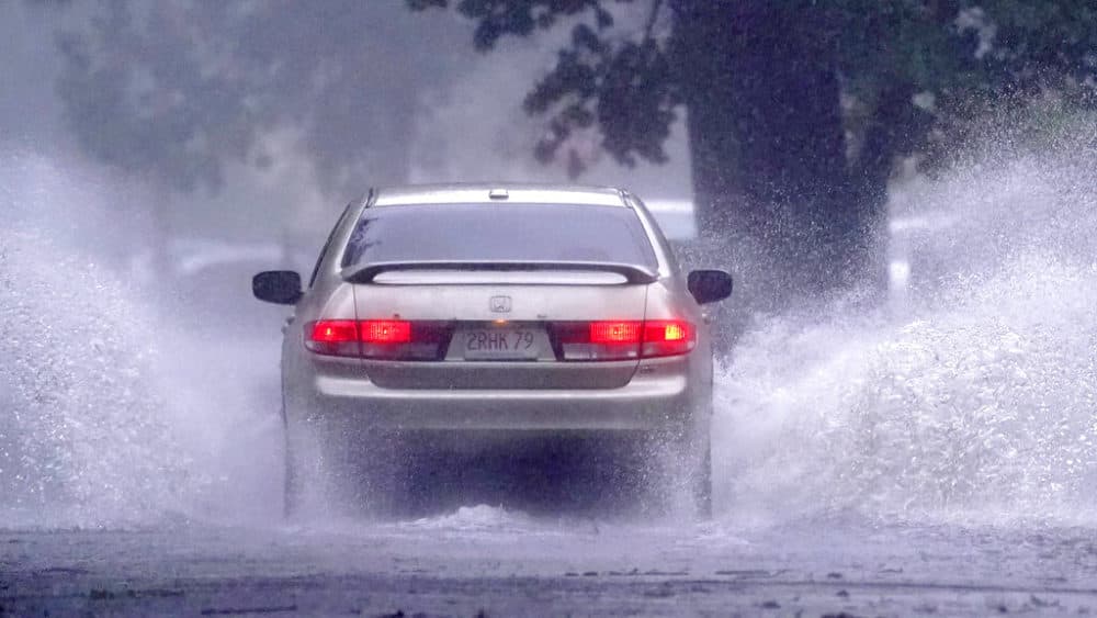 A car drives down a partially flooded street after the remnants of Hurricane Henri made landfall on Sunday in Springfield, Massachusetts. (Charles Krupa/AP)