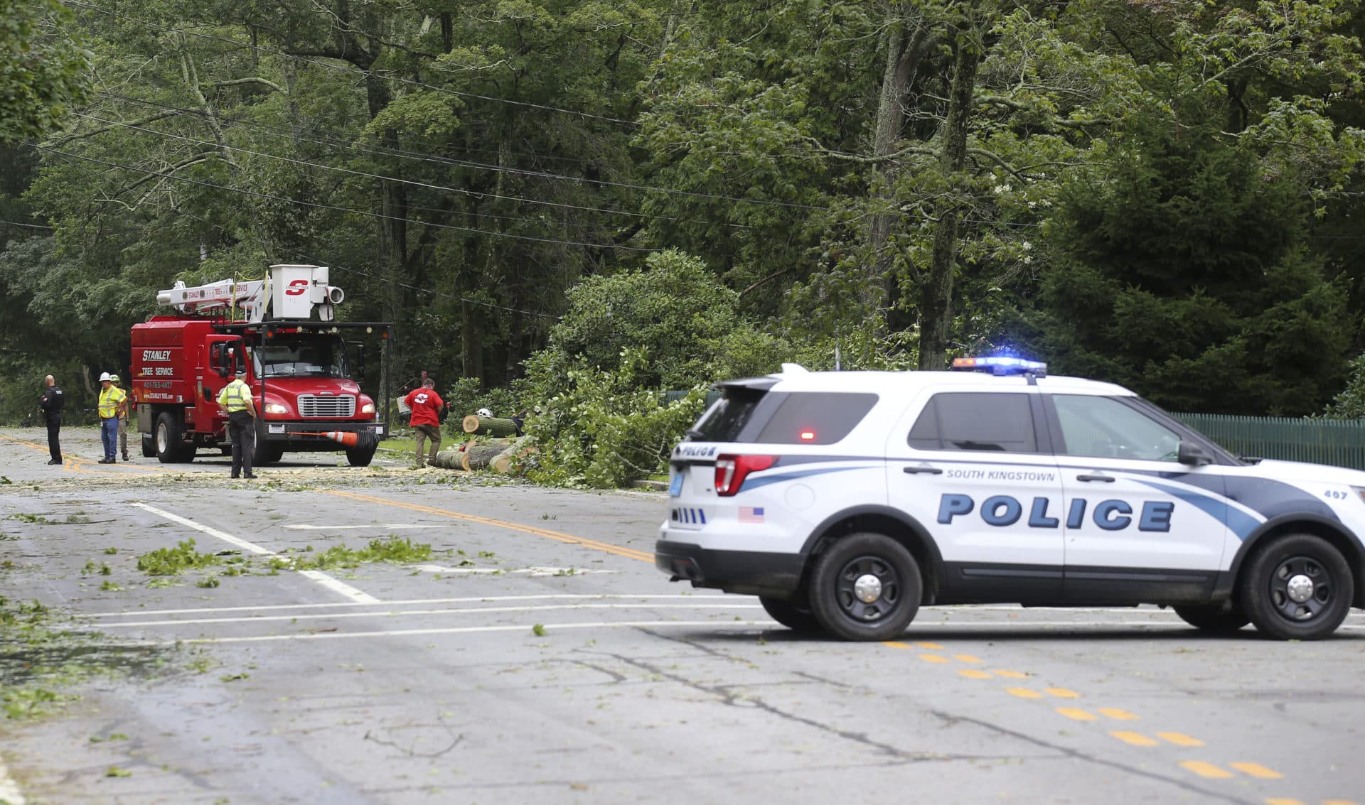 A crew works to remove a downed tree from blocking Route 138 in South Kingstown, R.I., Aug. 22, 2021. Strong winds from Tropical Storm Henri toppled many trees in the southern regional of the state. (Stew Milne/AP)