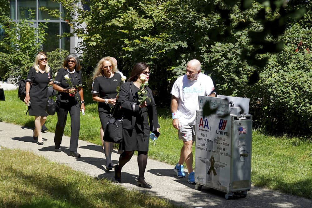 Paul Veneto, right, is joined by flight attendants as he pushes a beverage cart towards the 9/11 memorial at Logan Airport in Boston, on Saturday. (Mary Schwalm/AP)