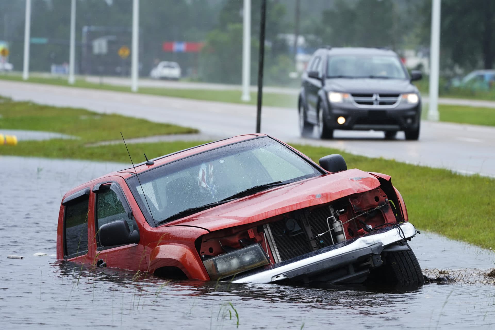 An abandoned vehicle is half submerged in a ditch next to a near flooded highway as the outer bands of Hurricane Ida arrive Sunday, Aug. 29, 2021, in Bay Saint Louis, Miss. (Steve Helber/AP Photo)