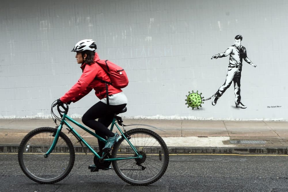 A cyclist passes a coronavirus-inspired piece of graffiti in Glasgow on April 4, 2020. (Andy Buchanan/AFP via Getty Images)