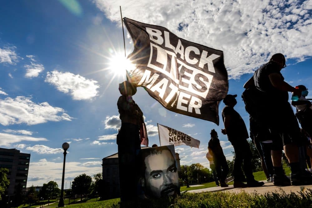 A woman holds a Black Lives Matter flag during an event in remembrance of George Floyd. (Kerem Yucel/Getty Images)