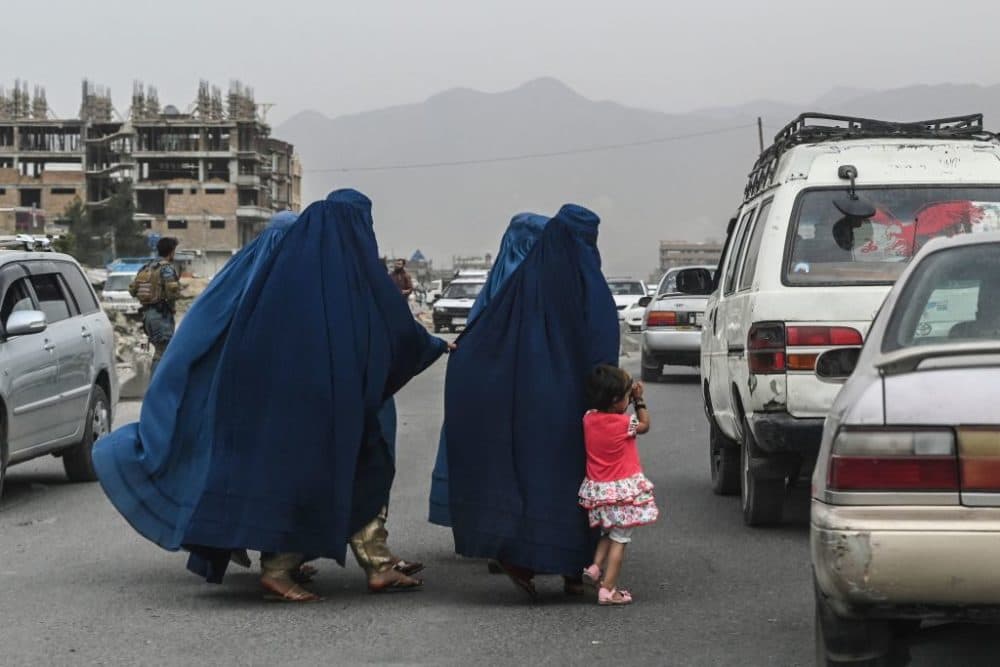 Women cross a road as they walk toward a local taxi in Kabul, Afghanistan, on July 31, 2021. (Sajjad Hussain/Getty Images)
