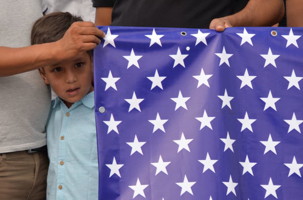 Afghan refugees, who fled Afghanistan in 1996, hold US flag as they attend a rally in front of the U.S. Embassy in Bishkek, on Aug. 19, 2021. (Vyachslav Oseledko/AFP/Getty Images)
