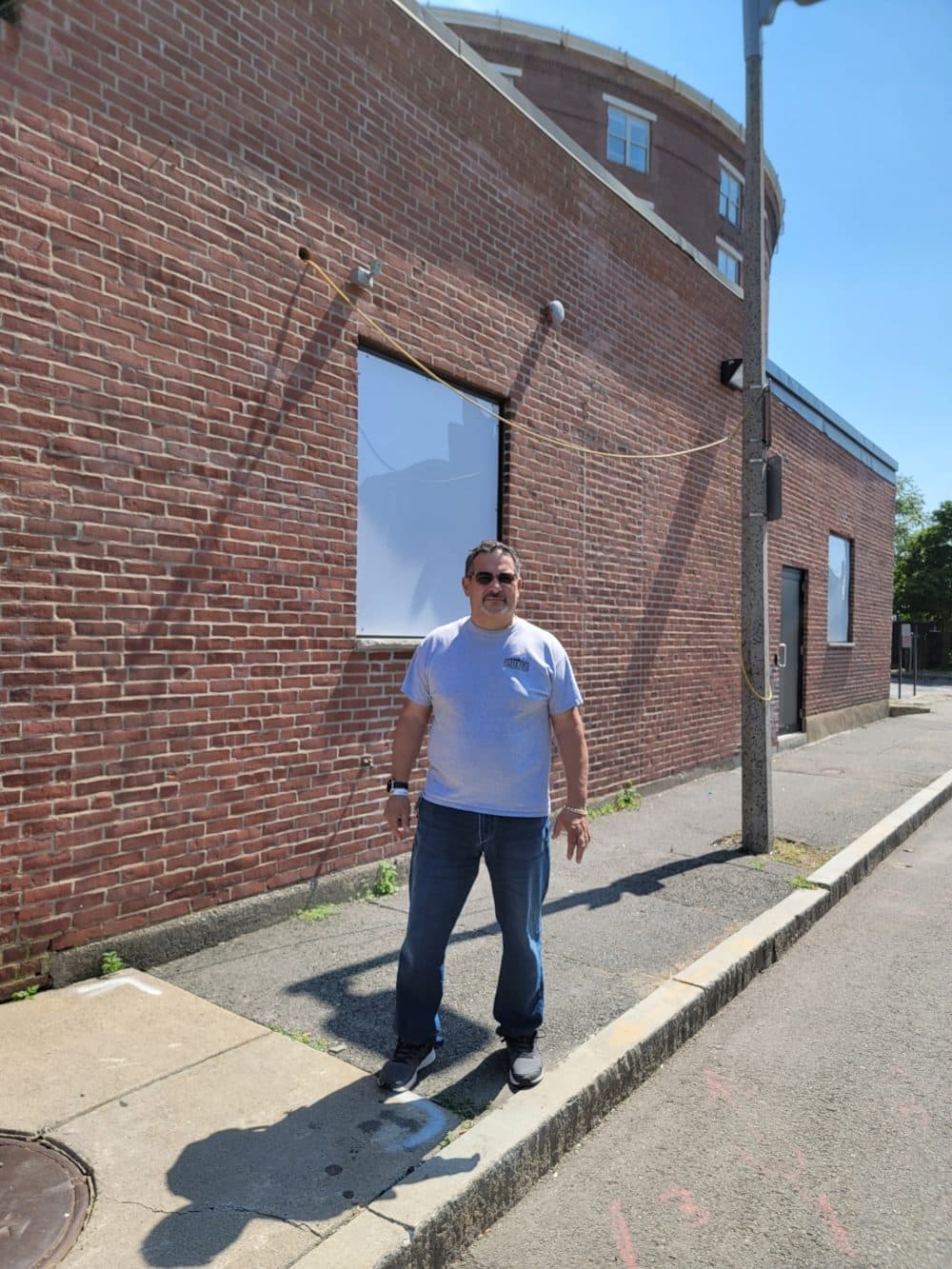 Gerry DiPierro in front of his company, DiPierro Construction. He covered the windows with plexiglass because of problems with theft and vandalism. (Deb Becker/WBUR)