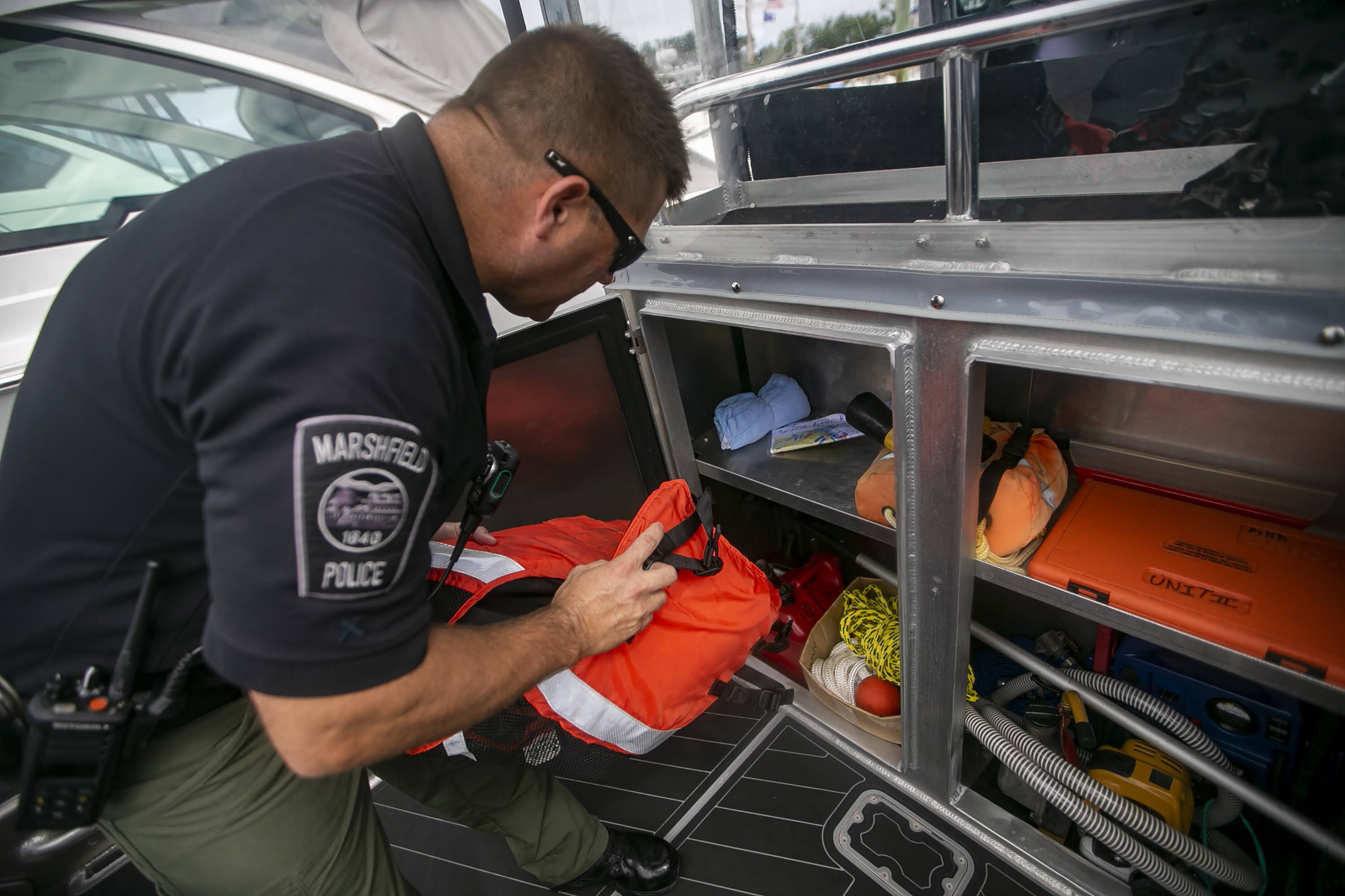 Marshfield Harbormaster Michael DiMeo pulls out a life vest before heading out on patrol. (Jesse Costa/WBUR)