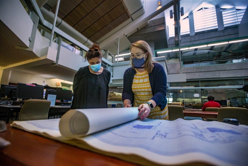 Caitlin Jones, Head of Reference Services at the Mass. Archive, rolls out and shows Laura Zigman the blueprints of the Fernald School in Waltham. (Jesse Costa/WBUR)