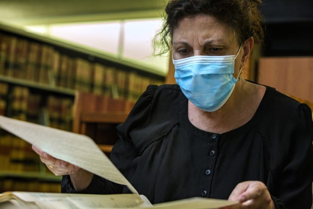 Laura Zigman flips through old administrative documents from the Fernald School in Waltham at the state archives in hopes of finding clues about her sister who was once a resident there. (Jesse Costa/WBUR)