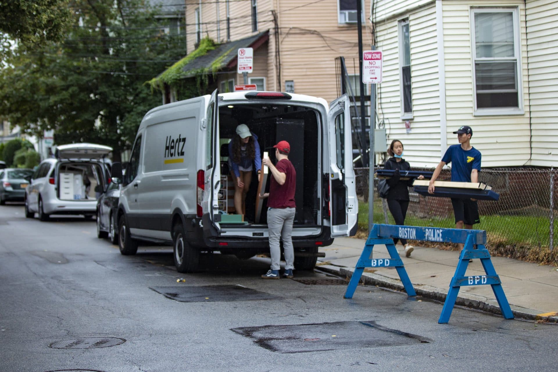 People move their belongings out of vans on Ashford Street. (Jesse Costa/WBUR)