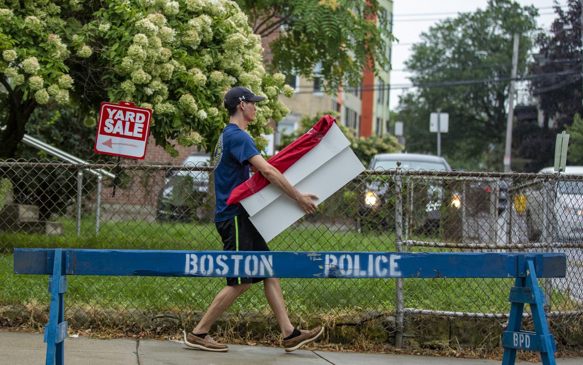 A man carries a box down Ashford Street in Allston Wednesday. (Jesse Costa/WBUR)