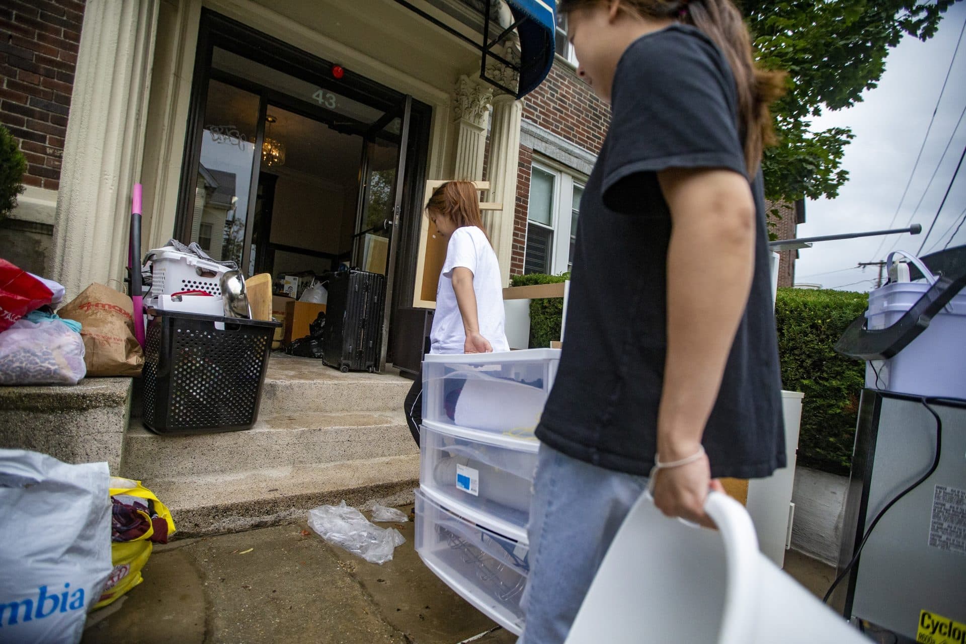 Two people move belongings into a building on Linden Street in Allston on Sept. 1. (Jesse Costa/WBUR)