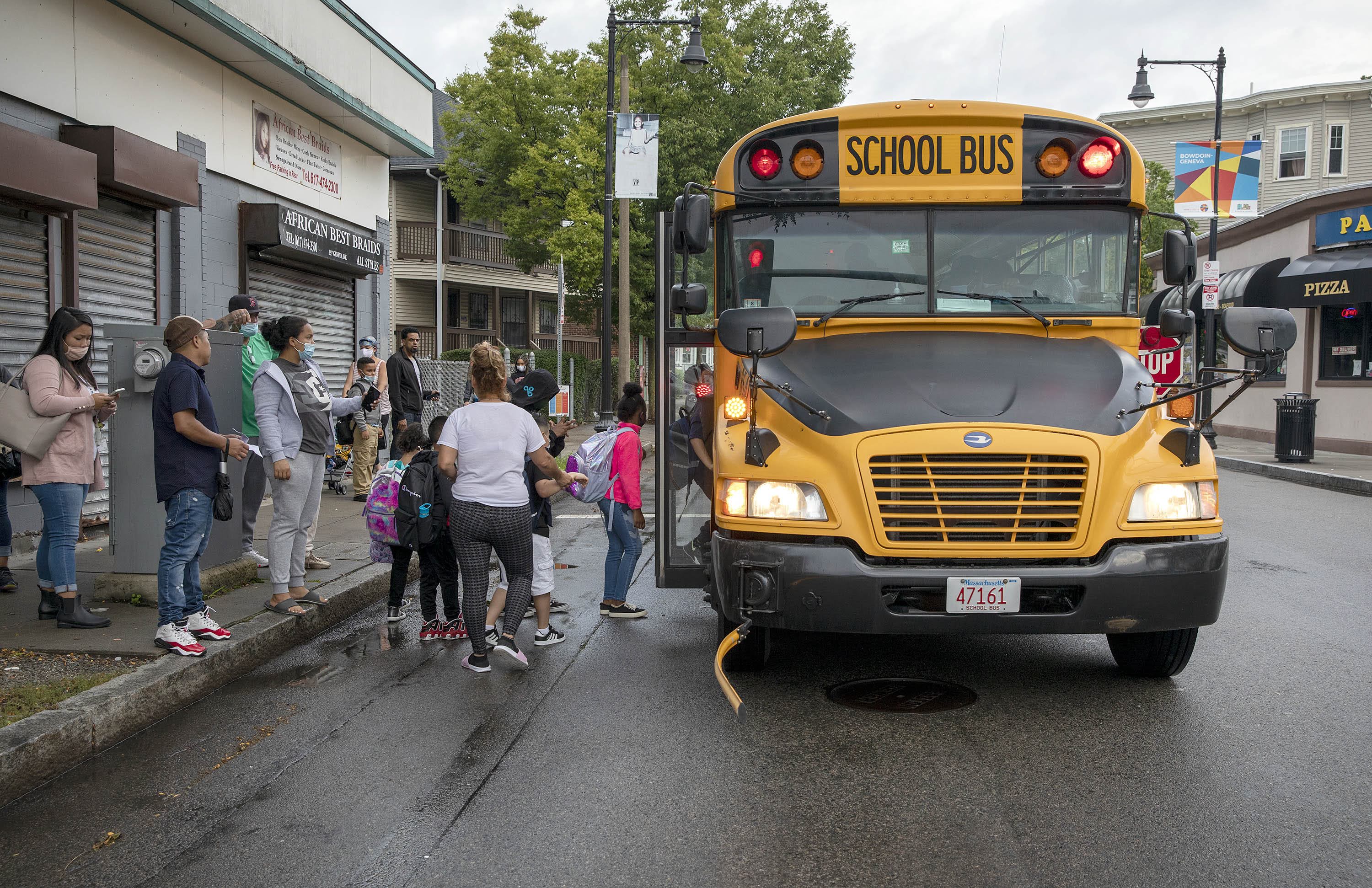 Families watch as kids board a school bus on Geneva Ave. in Dorchester for the first time this school year. (Robin Lubbock/WBUR)
