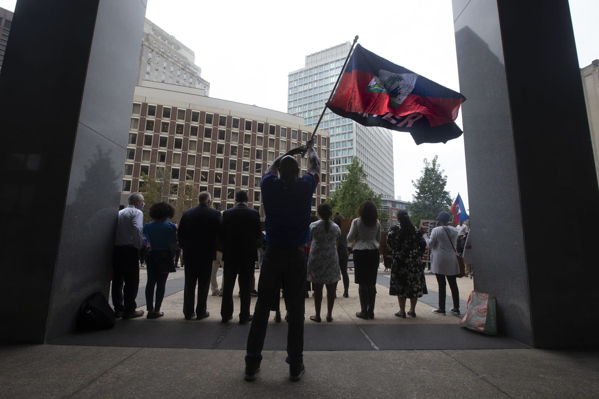 Jean Alfred Sandaire waves a Haitian national flag and a Black Lives Matter flag during the Solidarity with Haiti demonstration at John F. Kennedy Federal Building in Downtown Boston. (Jesse Costa/WBUR)