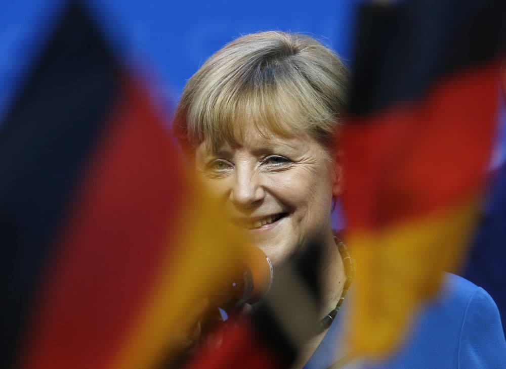 German chancellor Angela Merkel smiles behind German flags at the party headquarters in Berlin, Sunday, Sept. 22, 2013. (Michael Sohn/AP)