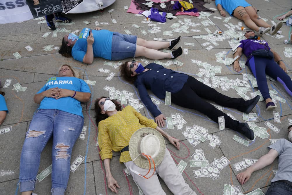 Protesters, including photographer and activist Nan Goldin, center right, stage a die-in and have their shapes traced on the sidewalk outside the courthouse where the Purdue Pharma bankruptcy is taking place in White Plains, N.Y., Aug. 9, 2021. (Seth Wenig/AP)