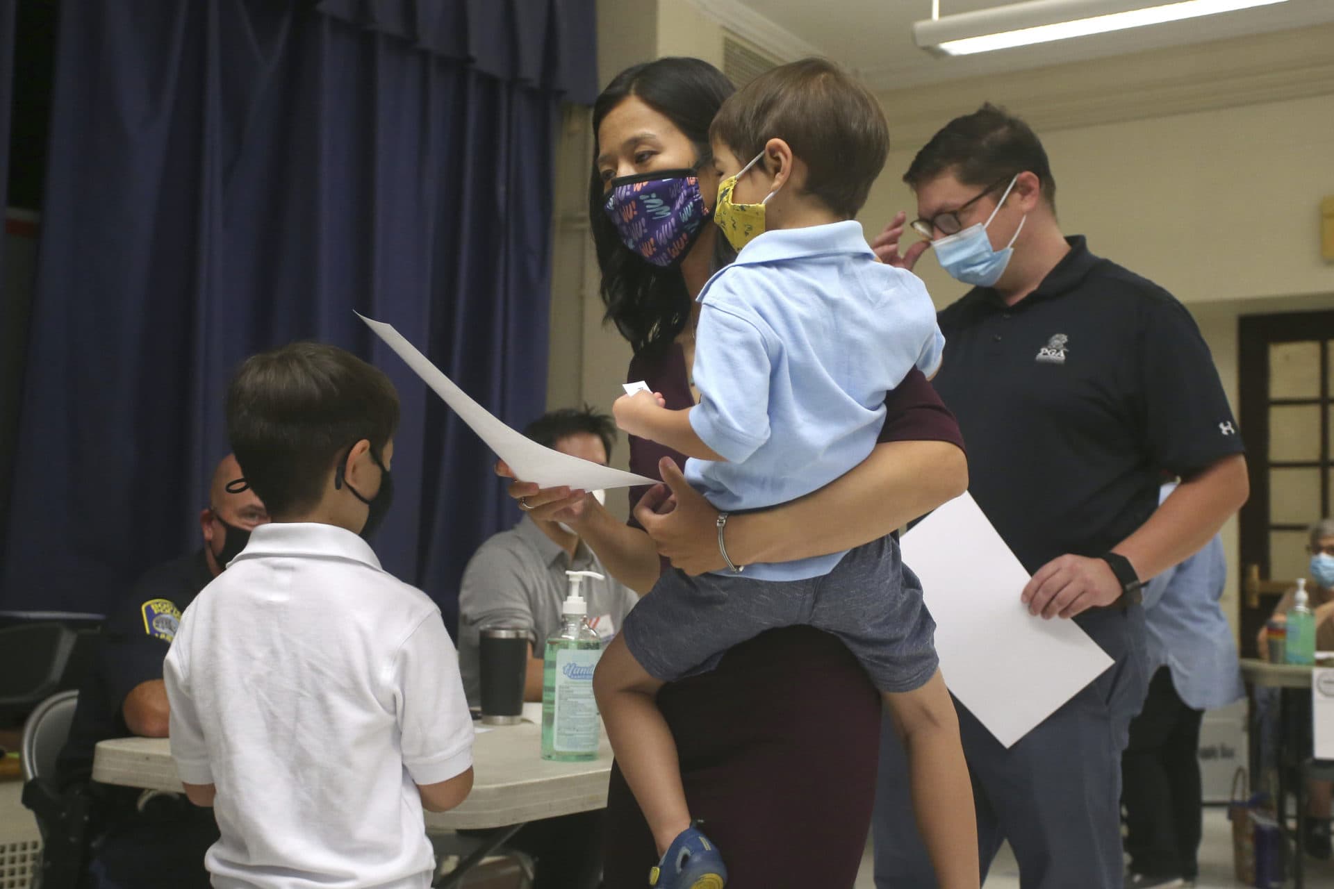 Boston mayoral candidate Michelle Wu, holding her son Cass, age 4, casts her ballot in the Mayoral race on Election Day, along with her husband Conor Pewarski, right, and their other son Blaise, left, age 6, at the Phineas Bates Elementary School in Boston, Tuesday, Sept. 14, 2021. (Stew Milne/AP)