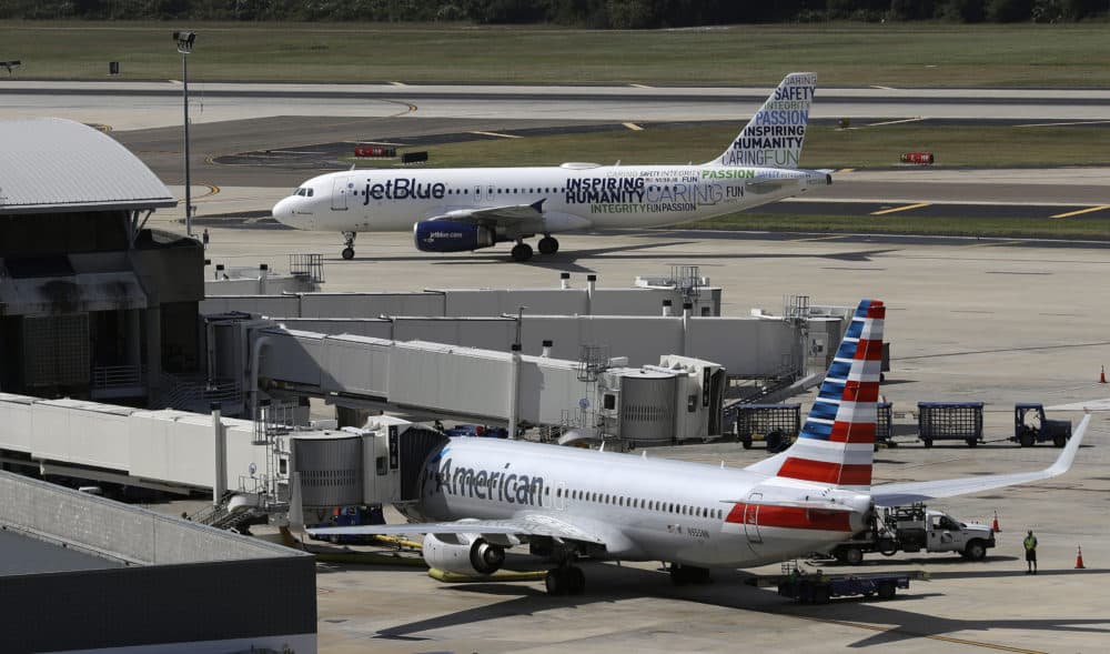 A JetBlue Airbus taxis to a gate as an American Airlines jet is seen parked at its gate at Tampa International Airport in Florida. (Chris O'Meara/AP)