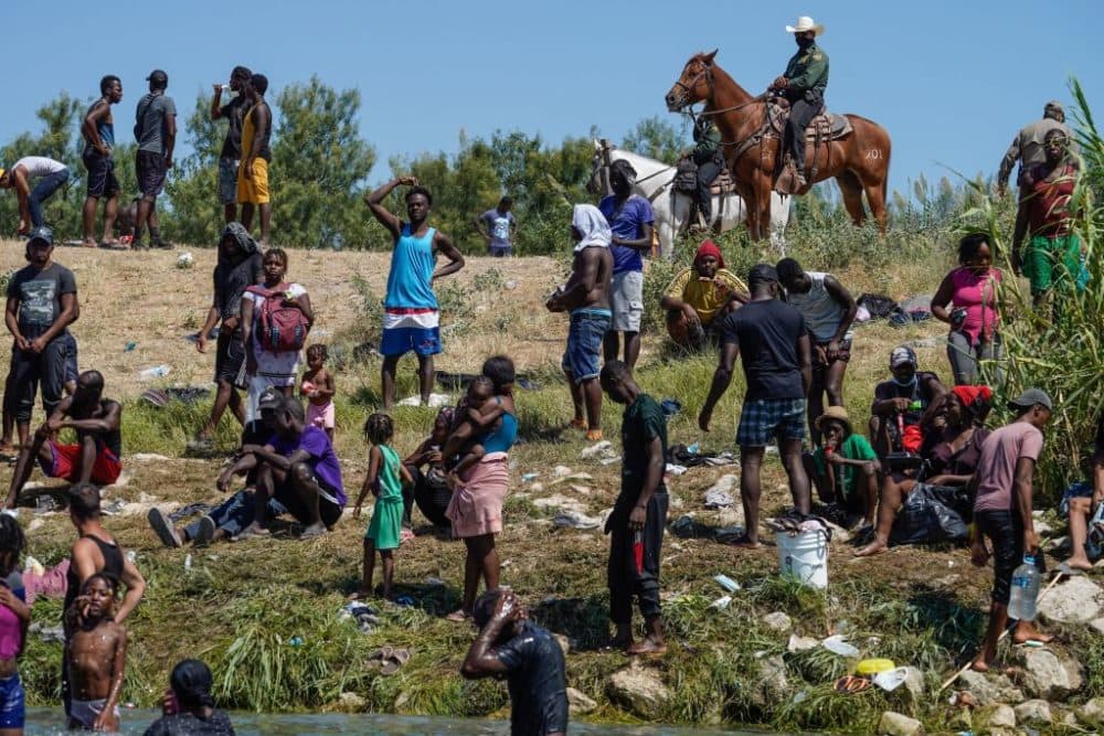 U.S. Border Patrol agents on horseback look on as Haitian migrants sit on the river bank near an encampment on the banks of the Rio Grande in Del Rio, Texas, on Sept. 19. (Paul Ratje/Getty Images)