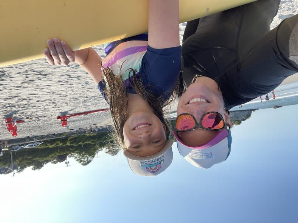 The author and her daughter Maya at the beach, with "big banana," the surfboard. (Courtesy Sara Shukla)