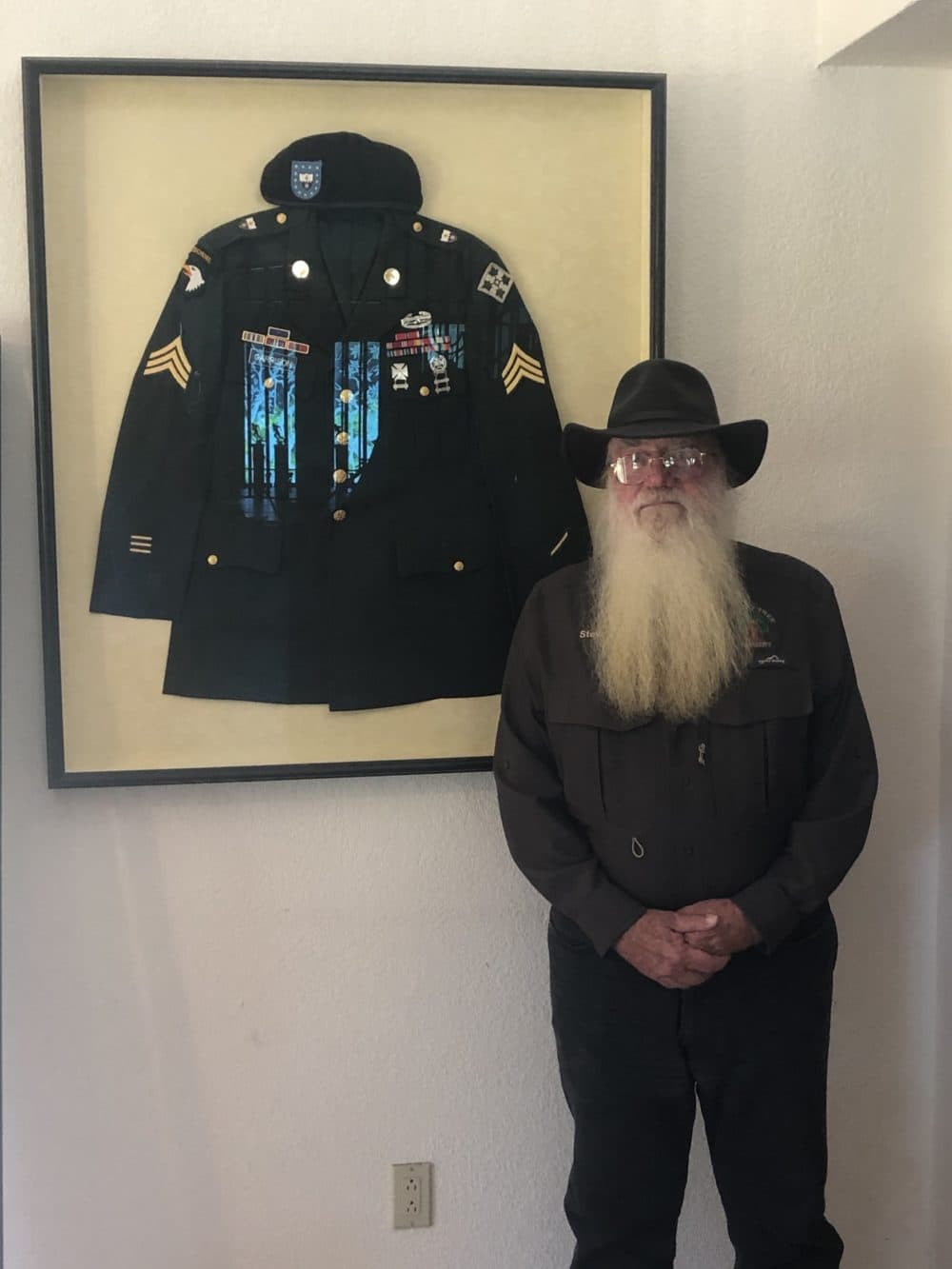 Stephen Garrison of the Flowery stands in front of his son Matt's military form during WLRN journalist Chris Remington's visit to his home in May. (Courtesy)