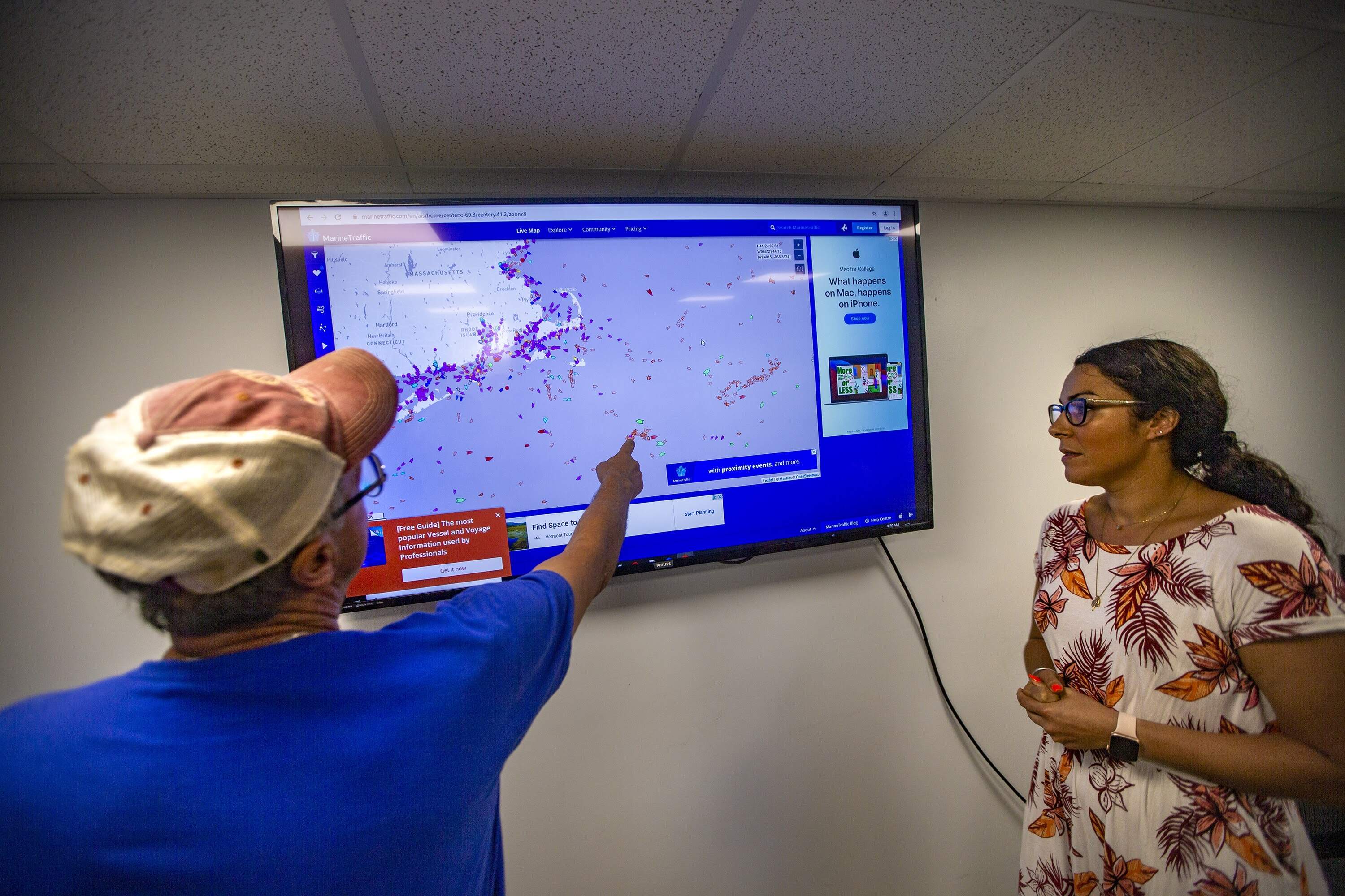 Director of operations at the Buyers and Sellers Exchange Seafood Auction House, Cassie Canastra watches as New Bedford scallop fisherman Tony Alvernaz points out how congested fishing traffic can become out on the Atlantic Ocean. (Jesse Costa/WBUR)