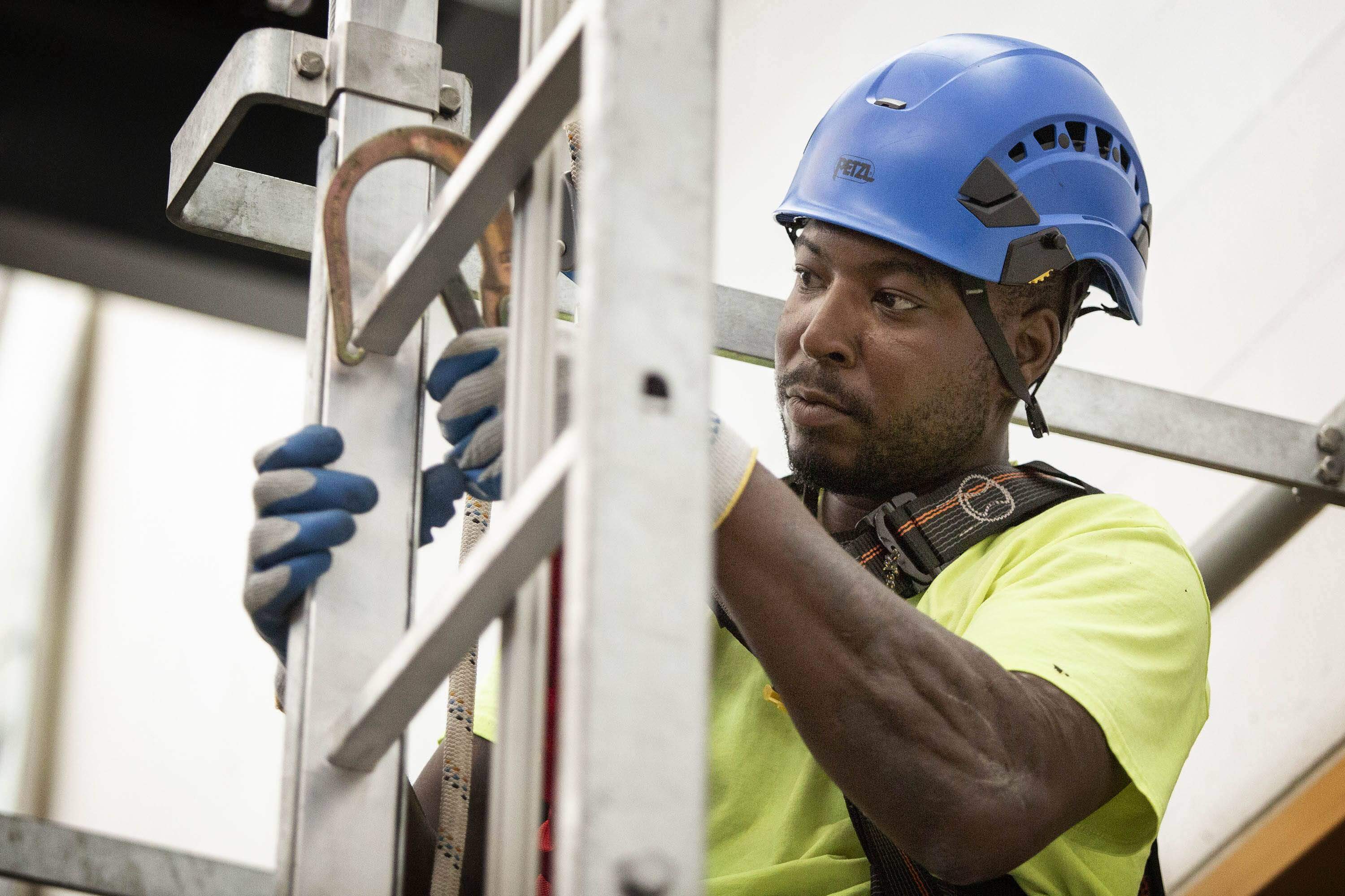 Ironworker Oronde Hale anchors himself onto a ladder during training. (Robin Lubbock/WBUR)