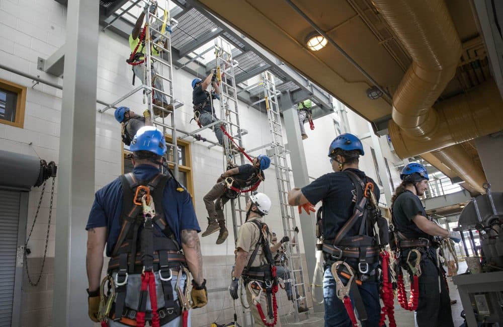 Trainees at the Working At Heights training session at the Massachusetts Maritime Academy practice rescuing an injured colleague. (Robin Lubbock/WBUR)