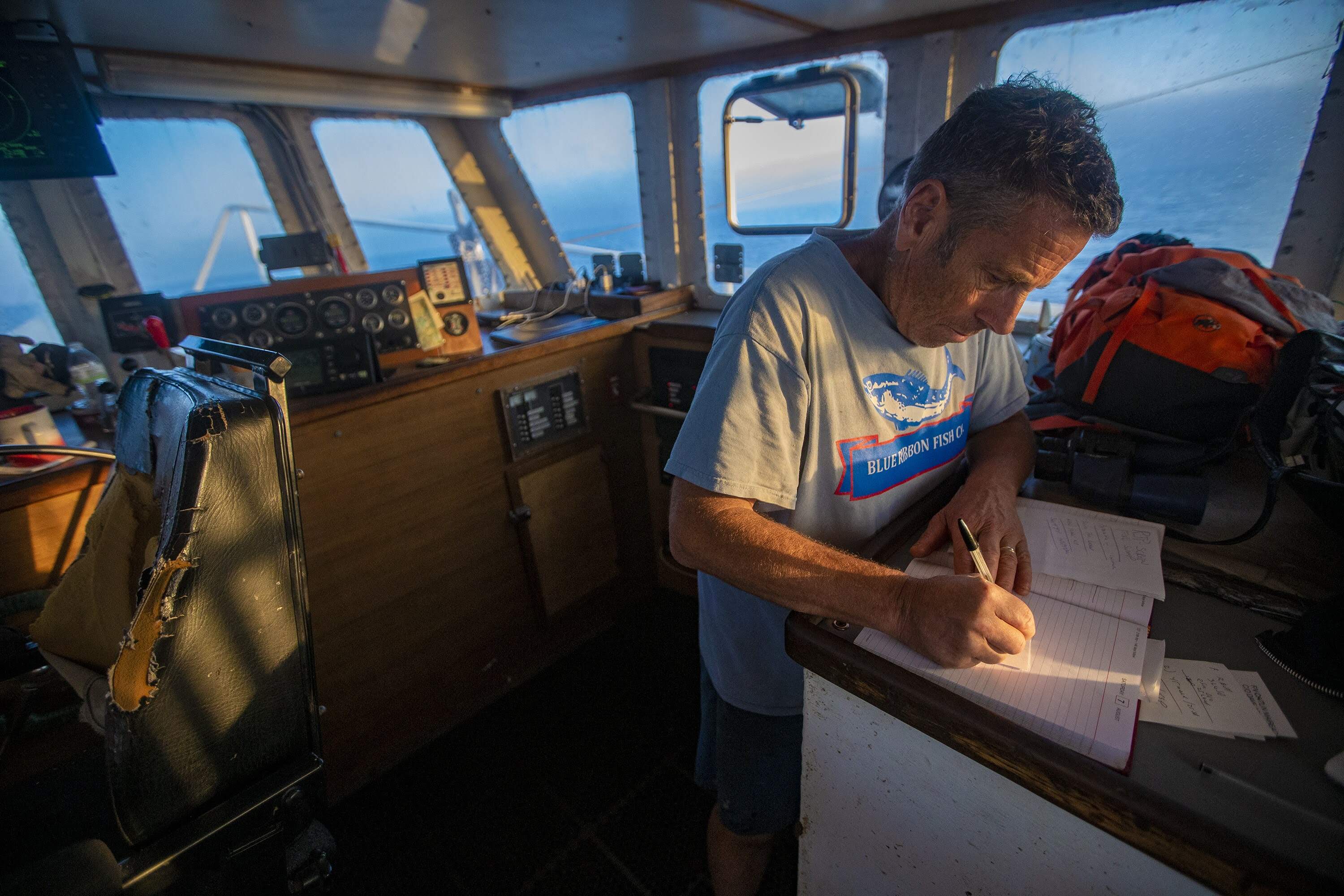 As the Caitlin & Mairead makes it’s way out of Lake Montauk into Gardners Bay, Dave Aripotch takes notes of the trip in a log book. (Jesse Costa/WBUR)