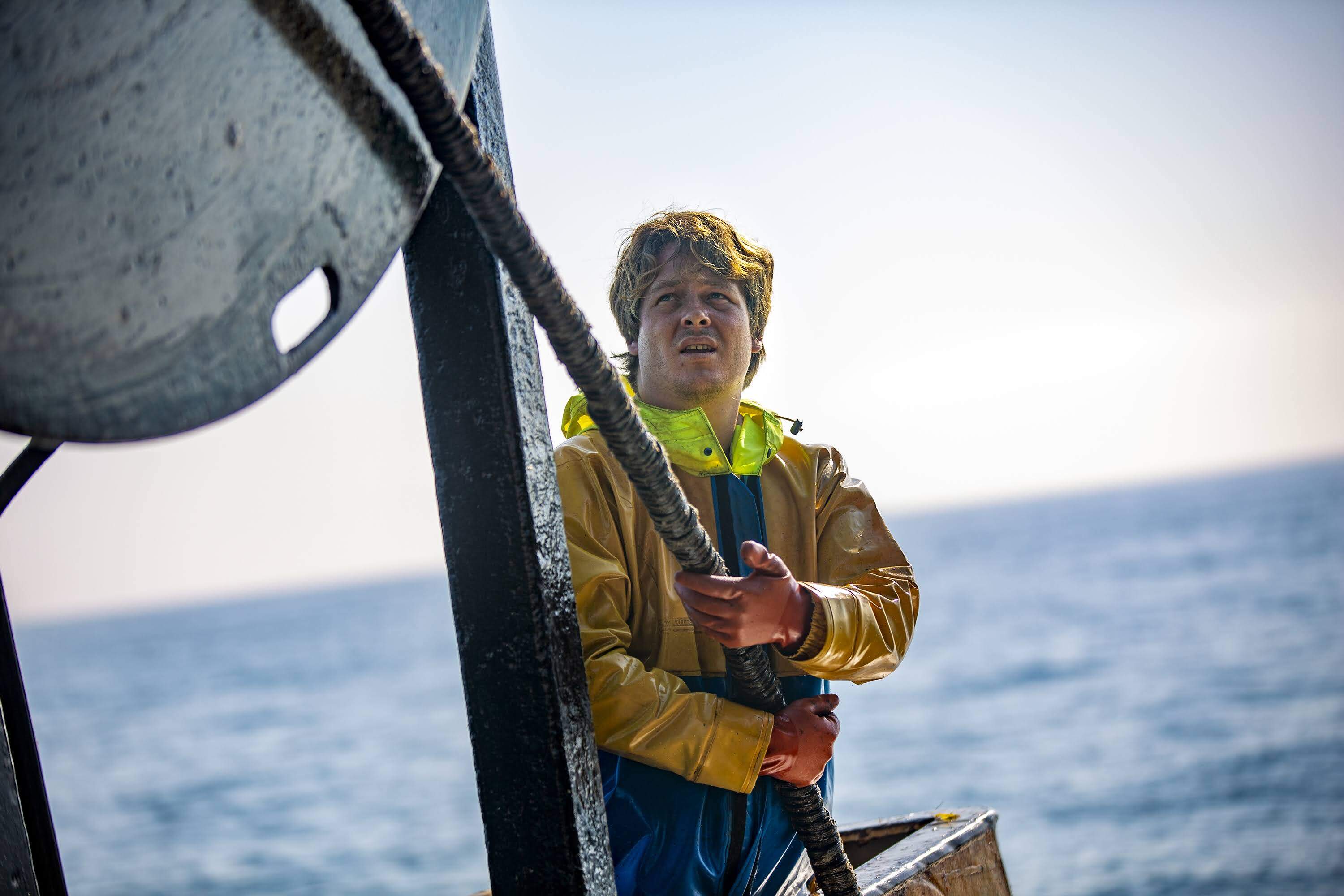 Joey Hodnik guides one of the Caitlin & Mairead’s fishing net lines as it is being released into the water trawling from squid in Gardeners Bay. (Jesse Costa/WBUR)