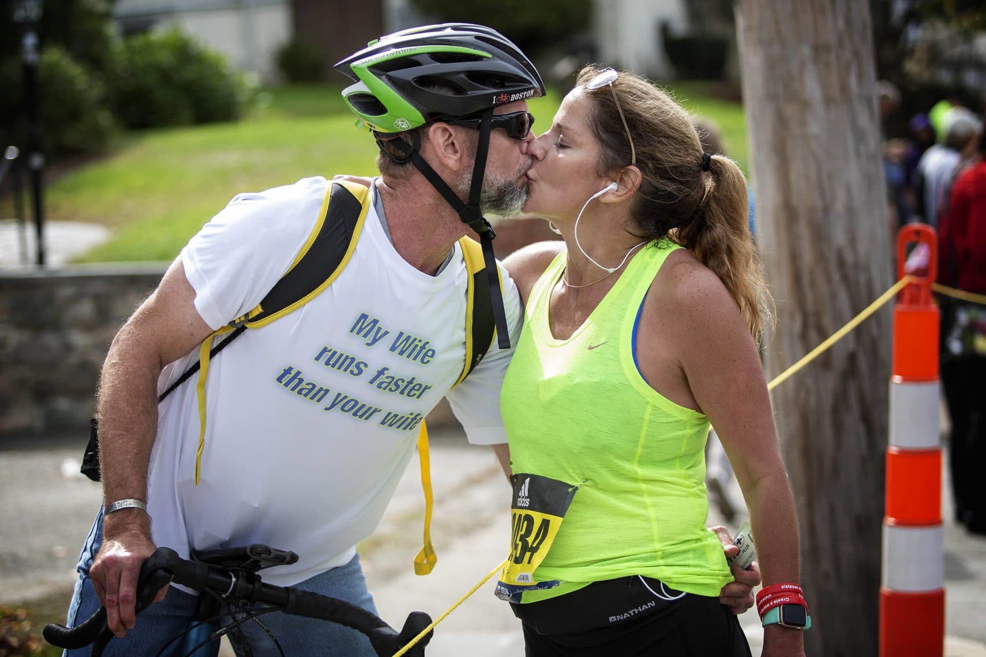 Melissa Rothe stops at mile 17 to kiss her husband Richard, who showed his support by following her along the marathon route on his bicycle. (Robin Lubbock/WBUR)