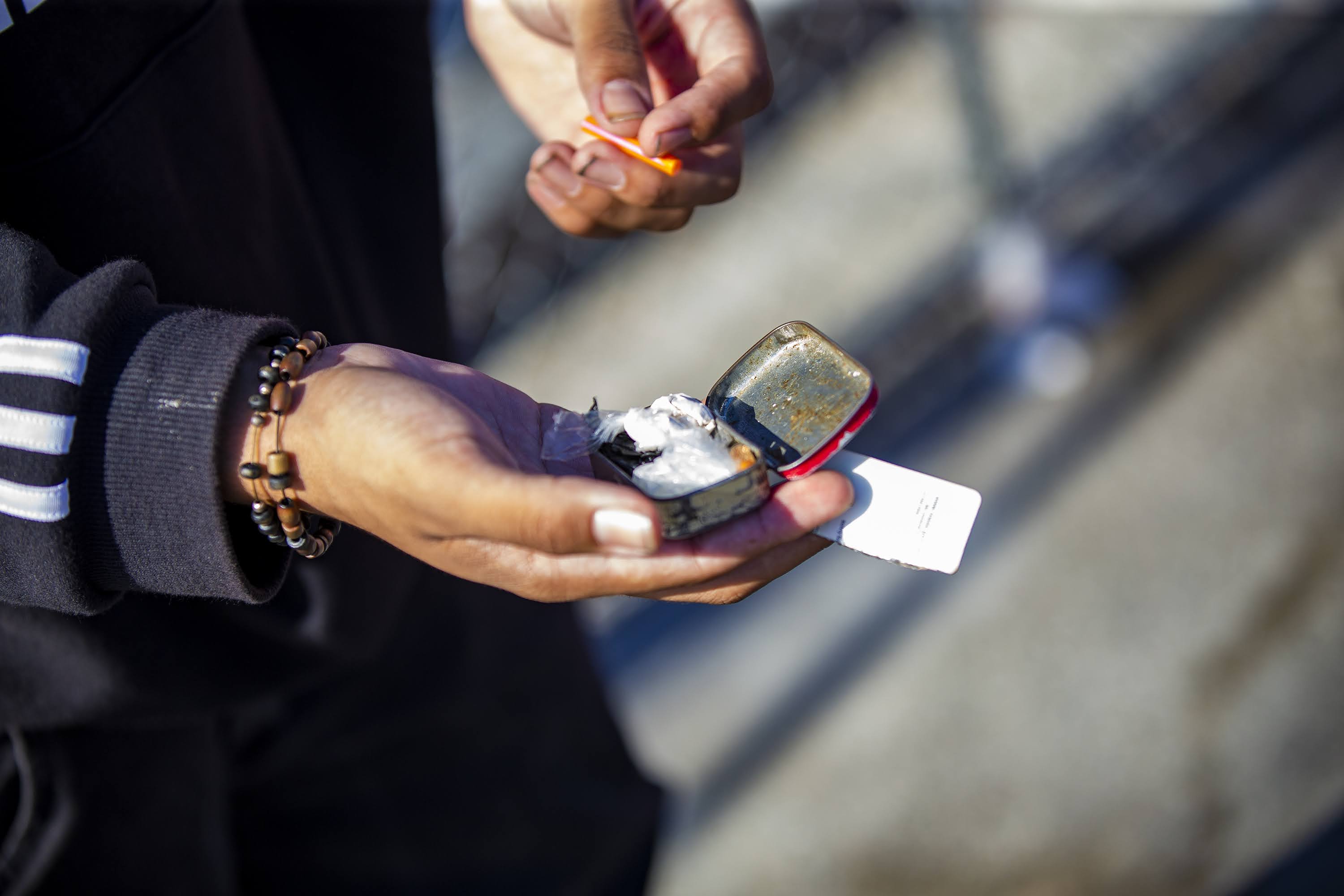 "Cabbi" opens a mint tin full of various drugs and paraphernalia on Atkinson Street. (Jesse Costa/WBUR)
