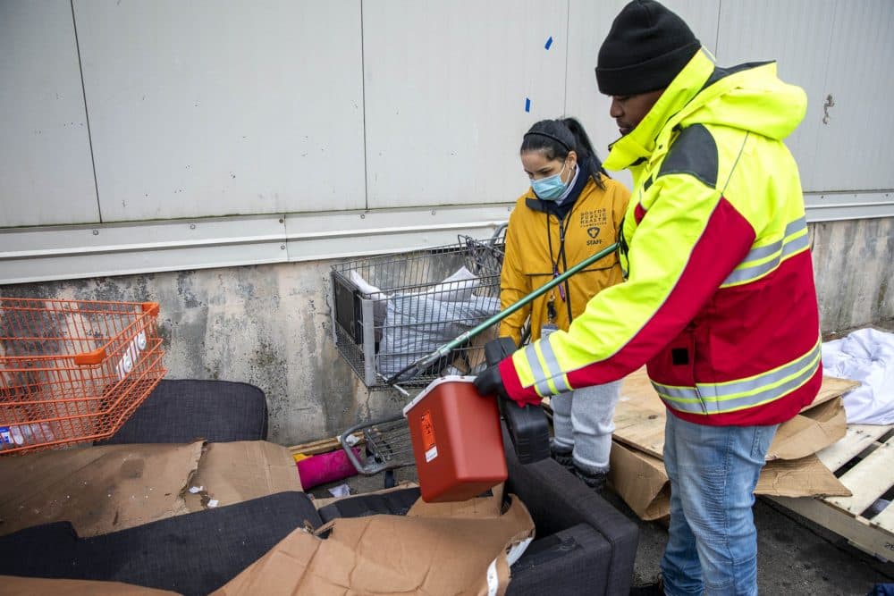 Boston Public Health Commission workers collect needles as work begins to remove a row of shelters the homeless community created on Southampton Street. (Robin Lubbock/WBUR)
