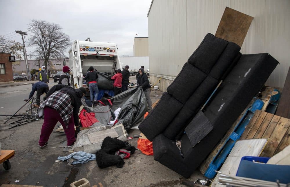 A Boston Public Health Commission crew throws materials and furniture from makeshift shelters on Southampton Street into a garbage truck. (Robin Lubbock/WBUR)