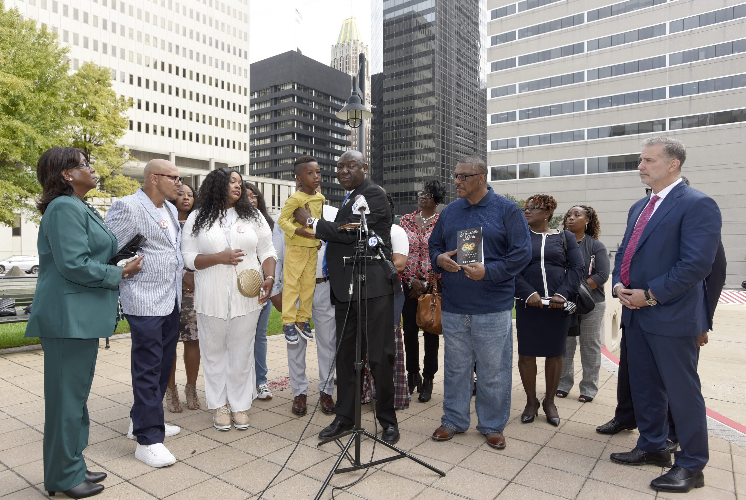 Attorney Ben Crump, center, holds Zayden Joseph, 6, the great-grandson of Henrietta Lacks, while standing with attorneys and other descendants of Lacks, whose cells have been used in medical research without her permission, outside the federal courthouse in Baltimore, Monday, Oct. 4, 2021. (Steve Ruark/AP)