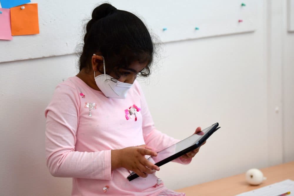 A pupil, wearing a protective face mask, works with an iPad during a summer project. (Ina Fassbender/AFP via Getty Images)