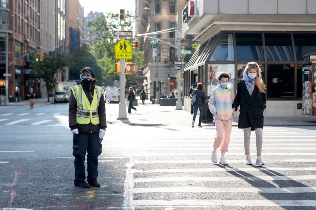 A school crossing guard stands in the street while a mother and child walk in the crosswalk on September 22, 2020 in New York City. (Alexi Rosenfeld/Getty Images)